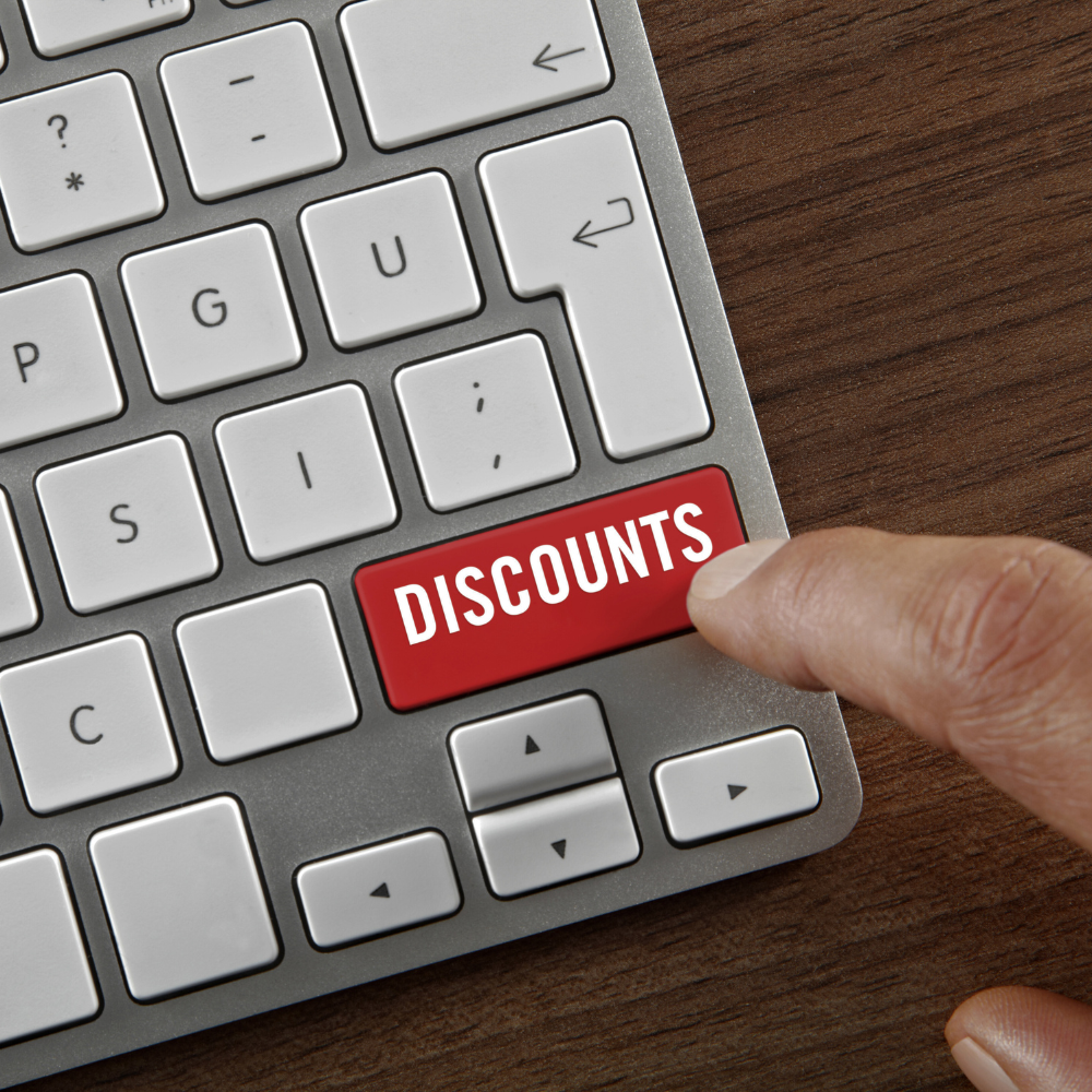Keyboard with a red 'DISCOUNTS' button being pressed by a finger on a wooden surface